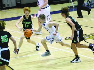 CCMS eighth grader Jaden Sevcech splits two  Dragons as he pushes the ball up the court last Thursday. 