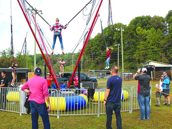 Fathers take photos and make videos of their kids bungee jumping up and down at the Apple Festival.