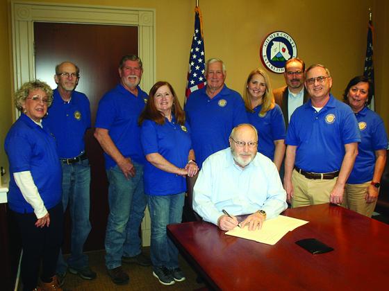 Members of the Gilmer County Optimist Club join Board of Commissioners Chairman Charlie Paris, seated, as he signs a proclamation recognizing Optimist Day in the county. Pictured in back, from left: Barbara Simmons, Bob Salman, Ed Grant, Lisa Salman, Bryan Staggs, club treasurer Rebecca Harrell, Probate Judge Scott Chastain, club president Trent Sanford and Ellen Grant.