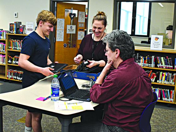 Carson Bentley was one of many students to be directed to the media center at Gilmer High School Friday, March 13, to receive an assigned Chromebook laptop. Manning one of the tables were assistant principal Tiffany Boyette and Erin Brandy (sitting).