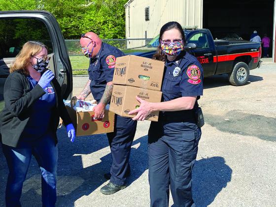 While loading boxes at the Gilmer Community Food Pantry, volunteer Pamela Kucera and Gilmer Fire and Rescue employees Mike Williams and Mary Fuller wear protective face masks made by members of Stay Active Ellijay. 