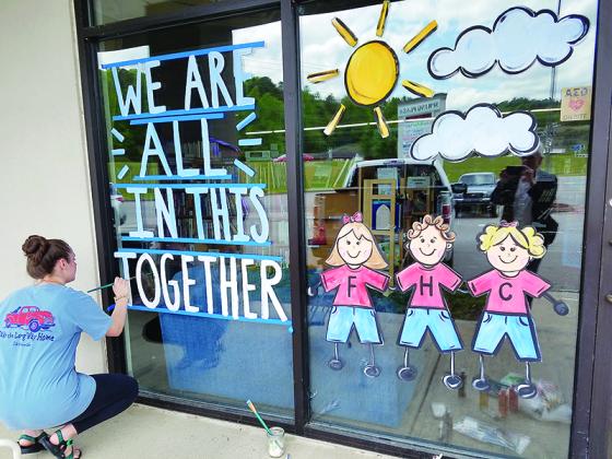 Dotson puts the finishing touches on a mural and positive message in the window of Faith, Hope and Charity Recycle Store.
