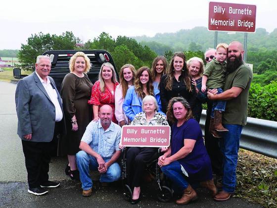 Above, family of Billy Burnette stand next to a new commemorative marker placed at the Highway 515 bridge over Talona Mountain Road last Friday. From left, front: Brett Burnette, Betty Hicks Burnette and Paula Holder; back: Georgia House Speaker David Ralston, Candace Poole, Stephanie Burnette, Bree Burnette, Bethany Burnette, Baylee Burnette, Holli Holder, Linda Burnette, Tommy Burnette, Cooper Poole and Brian Poole.