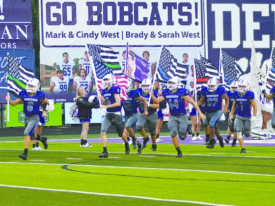 Gilmer High School senior football players carry flags onto the field last Friday to honor first responders and military personnel. 