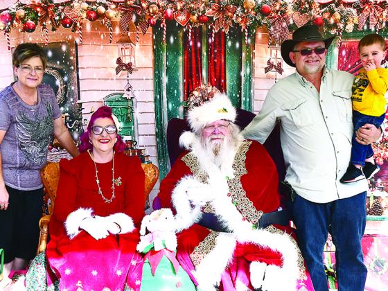 Cooper Rollins, right, enjoys his Santa time with grandparents Bobbie and Glen Goldman.
