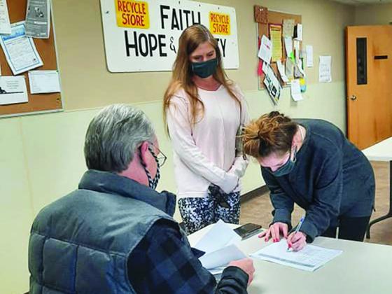 Kent Sanford, of the Faith, Hope and Charity Scholarship Committee, helps two students during the nonprofit’s recent award process for the spring college semester.  