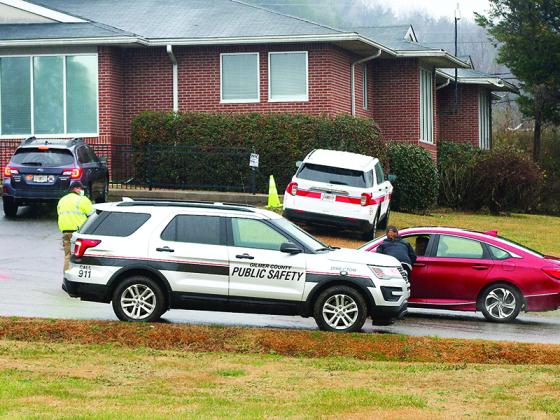 Gilmer County EMA Director Keith Kucera, left, and environmental health manager Andrea Mathis, at car window, assist with traffic control outside the local health department on Monday.