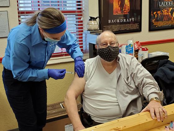 Paris is pictured getting his second dose of vaccine from Taylor Rayburn. 