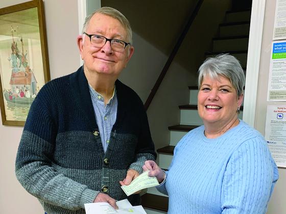 Safe Choice Pregnancy Care Center Director Rhenda Booth, right, gives a final check covering the center’s mortgage balance to Don Vanlandingham, the Sailors Drive building’s previous owner. 