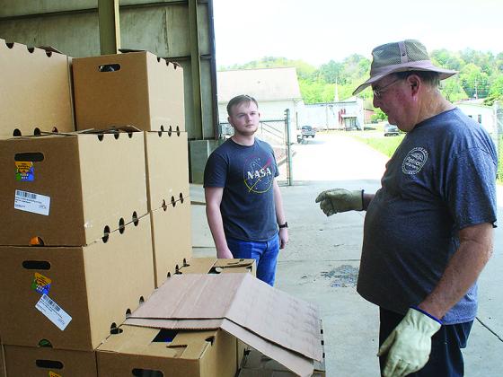 Gilmer Rotary Club member Charlie Pults, right, and Ryan Smiley, a member of the Gilmer High School Interact Club, work their way through a stack of Farmers to Families food boxes during a distribution day at the Amicalola EMC warehouse last week. 