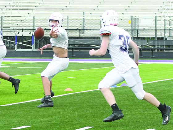 Gilmer High quarterback Seth Darling pitches the football to Gray McClure during a spring practice drill.