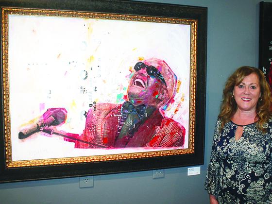 Claudia Bradford is pictured with a print of Ray Charles by her dad, Sidney Randolph Maurer, which is featured in an exhibit of Maurer’s work now on display at the Gilmer Arts Gallery.