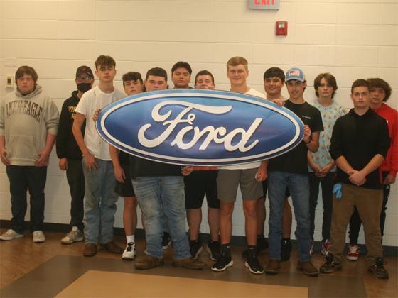 Students in an auto tech class at Gilmer High School hold up a banner supplied by Ford Motor Company. Auto tech classes at GHS completed the most Ford ACE certification courses in their region during the 2020-21 school year.