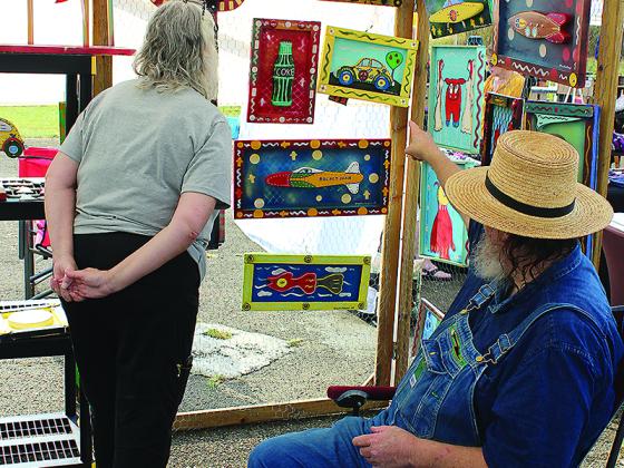 Folk artist Charles Dingler shows Susan Catron some of his creations during the 2019 Dancing Goats Folkfest.