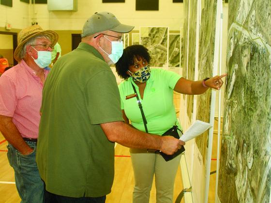 Georgia Transmission representative Dawn Jones, right, helps local business owners Dewell Sanford and Terry Hensley look at maps showing the route of a subtransmission power line proposed to run along Highway 515.