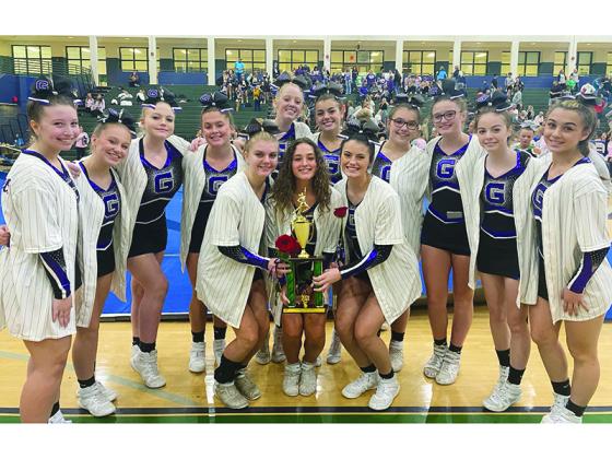Gilmer High School’s competition cheerleaders gather around their first-place trophy from last Saturday’s event.