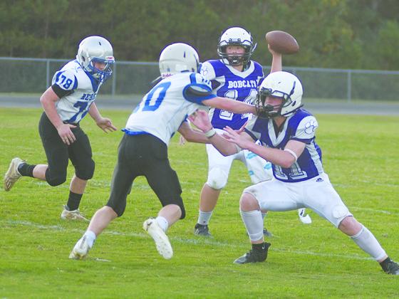 Clear Creek seventh-grade quarterback Jace McCollum scans the field for an open receiver behind the block of halfback Douglas Callihan.