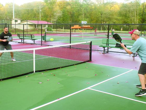 Eric Solgard, left, and Chris Chapman, right, knock out a round of pickleball at the Gilmer Park and Rec. courts following a brief rain Monday. The competitive game, which combines elements of tennis, badminton and ping-pong, is gaining a following locally. 