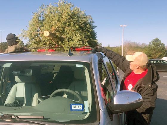 U.S. Army Corps of Engineers volunteer Red Clay, above, and Jett Reed and Miller Jane, below, help add to the pile of Christmas trees that were dropped off during a recent Keep Gilmer Beautiful recycling event at the East Ellijay Lowe’s.  