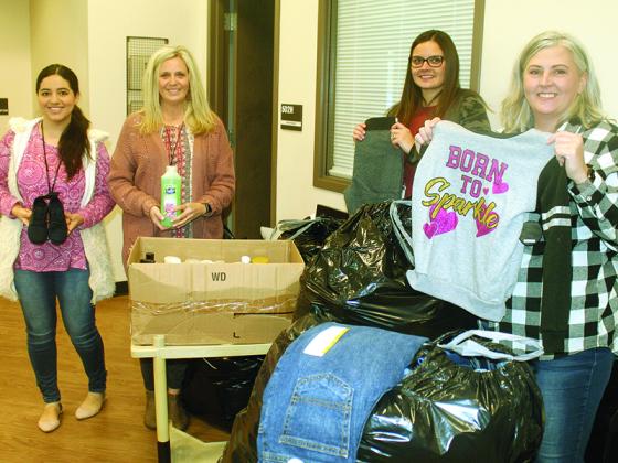 Luisa De Loera, Penny Griggs and Jessica Barclay, of Clear Creek Elementary School, receive Bring a Bundle Clothing Drive donations from Times-Courier staff member April Teague, right. 