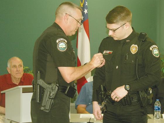 Ellijay Police Chief Ed Lacey pins a Lifesaving Medal on officer Austin McArthur, one of two officers commended at a recent city council meeting.