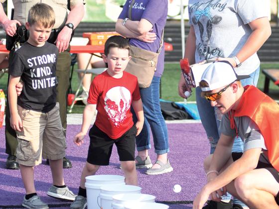 Kellen Parks, who is set to enter pre-K next school year, tosses a Ping-Pong ball into bucket at Kris Martinez’s Skills USA booth.