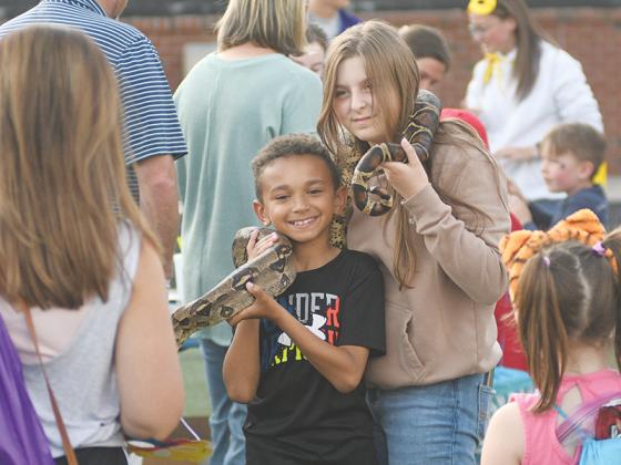 Second grader Lukas Campbell and sixth grader Camilla Tejeda hold Rocky, a 4-year-old red-tailed boa at Heath Hinton’s Exotic Animals Club exhibit.