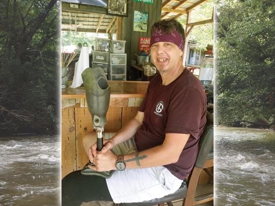 John Weaver poses with the prosthetic leg he lost in the Cartecay River four years ago; a diver from Tennessee found it downstream recently. Of the tattoo of a cross on his arm, he said there were “no doubts” God has helped him on his journey, and he wants it to be a witness. “That’s the reason I put it there,” he said. 
