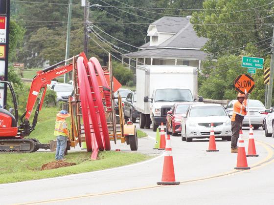Traffic waits as a length of protective conduit, which will encase power lines being moved underground, is installed along River Street. 