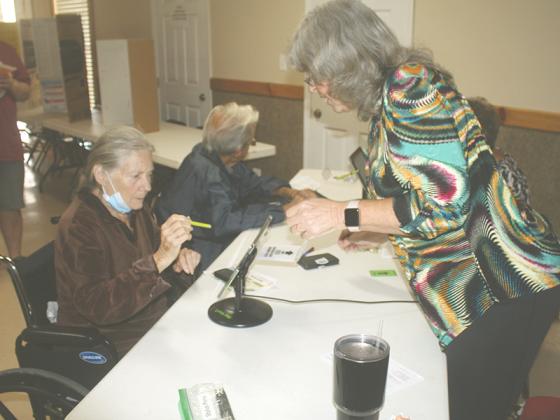 Poll officer Sherrill Davis, right, shows voter Frankie Love where to sign in on Election Day at the Ellijay North polling place.  