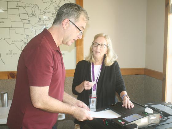 Mark Queen, left, turns in his ballot printout and gets a voter sticker from poll worker Linda Rogers at the Ellijay North polling place, the Coosawattee Shrine Club, Tuesday morning.  