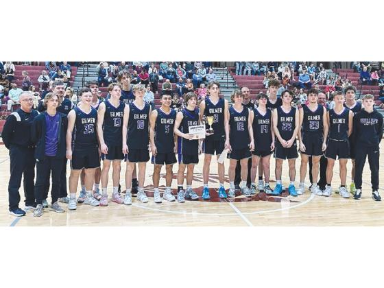 Gilmer High basketball players and coaches gather around the Bobcats’ runner-up trophy following the Region 7-3A championship game last Saturday in Dawson County.