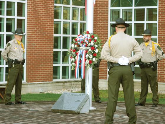 Honor guard members Cpl. Al Greenway, Deputy Ryan Scott and Sgt. Randy Beavers encircle a red, white and blue wreath placed at the memorial marker for Dickey outside the courthouse.
