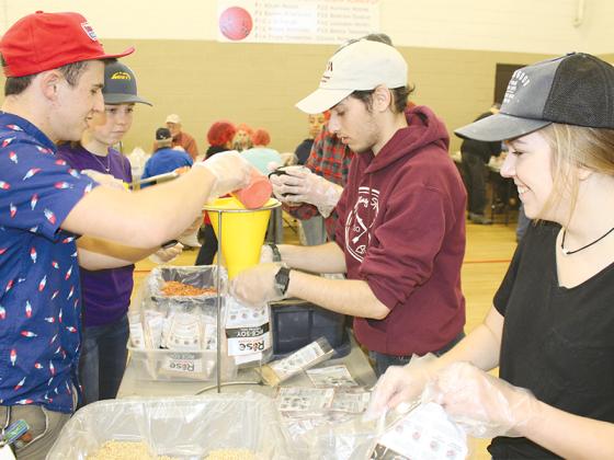 During the 2019 Rise Against Hunger effort in Gilmer County, Boy Scouts of America Adventure Crew members, from left, Skyler Smith, Cadence Smith, Grant Cromwell (hidden), Zack Kepley and Olivia Miller package meals at the Civic Center. The 2023 event is this Saturday morning at the same venue.