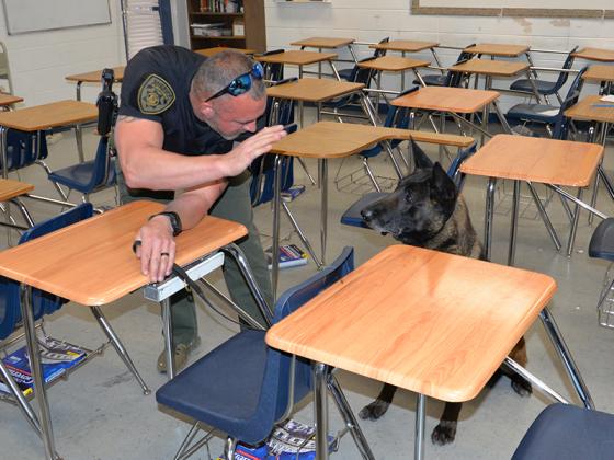 Gilmer County Sheriff’s Office Corporal David Ridings puts K-9 Milo through a brief training exercise at Fannin County High School in Blue Ridge after Milo and four other drug dogs thoroughly searched the school Wednesday, March 29.