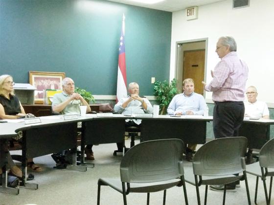Kent Sanford, of the Gilmer Initiative for Community Housing, standing, explains a new effort to build a workforce housing apartment complex, funded in part by state-issued tax credits, to Ellijay City Councilmembers and Mayor Al Hoyle. 