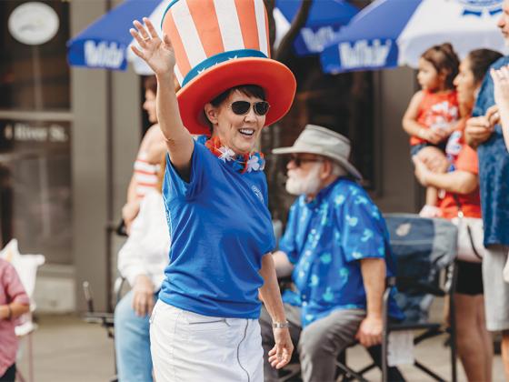A parade participant waves to the crowd. (@photosbylindsayann)