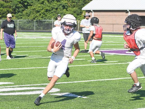 Gilmer head coach Paul Standard (left in black) looks on as quarterback Issac Rellinger makes his way around the corner at the Bobcats’ first practice in full pads.