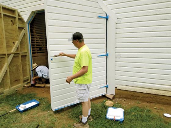 Rusty Raines, foreground, was among those applying three new coats of paint to the 100-year-old Pinson Barn at Harrison Park earlier this week. 