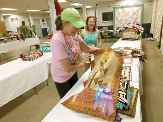 Quilters Gail Kivett, left, and Jeanne Carracher, right, show some of the winning quilt entries.