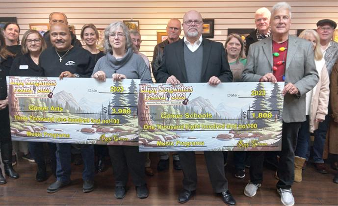 From front left, Gilmer Arts board president Terry Ellis, Gilmer Arts director Pam Burns and Gilmer Schools Superintendent Dr. Brian Ridley accept donation checks from Ellijay Songwriters Festival promoter Ray Green, right. The donated funds, which came from the May 2023 live music event, will be put toward programs offered by the two recipients.