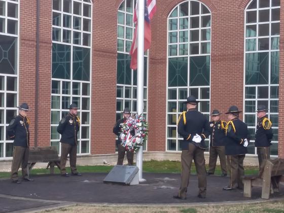 An honor guard comprised of Gilmer Sheriff’s Office personnel encircles a red, white and blue wreath placed at a marker at the base of the courthouse flagpole honoring Dickey. Pictured, from left: Al Greenway, Randy Beavers, Josh Easley, Greg Dotson, Jeff Ellington, Brian Crump and Ryan Scott.