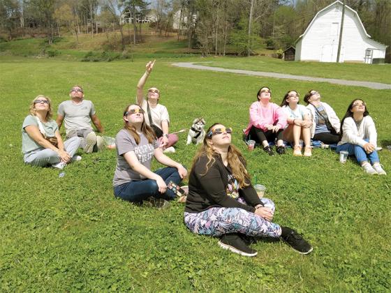 It didn’t get much darker than on an average stormy day, but that didn’t stop many in Gilmer County from enjoying a partial view of Monday’s total solar eclipse. Above, at Harrison Park, staff and friends of Ellijay’s BehaviorLink ABA therapy office use their eclipse glasses to to watch the rare celestial event unfold. 
