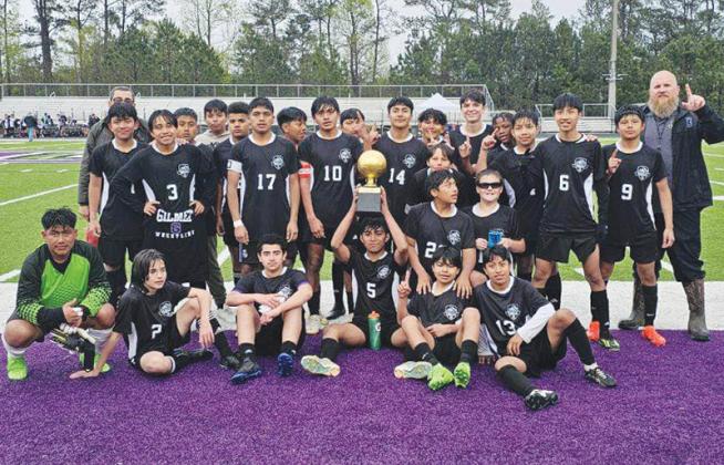 Clear Creek Middle School soccer players and coaches gather around the Bobcats’ Mountain League championship trophy April 9.
