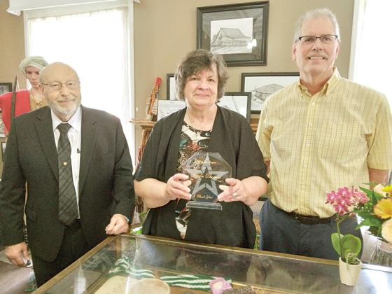 Retiring Gilmer County Historical Society President Leslie Thomas, center, accepts an award of appreciation from Commission Chairman Charlie Paris, left, and new historical society president Doug Piette, right. 