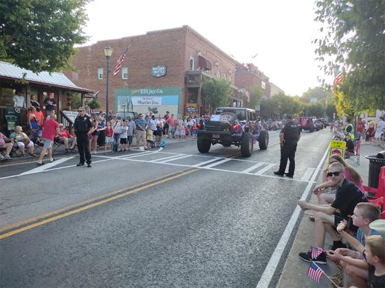 Ellijay police officers, from left, Doug Colburn, Jacob Chastain and Dawson Young (on sidewalk) keep River Street clear and safe for the Fourth of July parade in Ellijay. (Photo by Mark Millican)