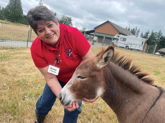 Sharon Callan, owner/operator/trainer at Shelter Dogs for Veterans, proves her ability by training a miniature donkey when she was at her ranch in the Seattle/Tacoma, Wash., area. On facing page, the Shelter Dogs for Veterans logo, with its Post-Traumatic Stress Disorder (PTSD) and Traumatic Brain Injury (TBI) acronyms. (Contributed photo)