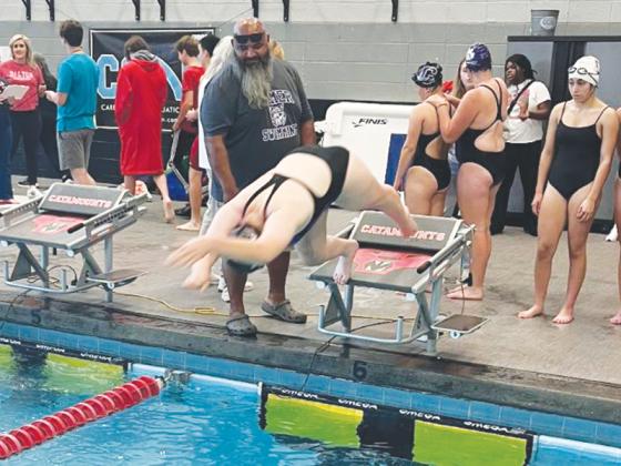 Gilmer’s Elizabeth Kucera dives into the pool last Saturday as coach Alton Guidry looks on.