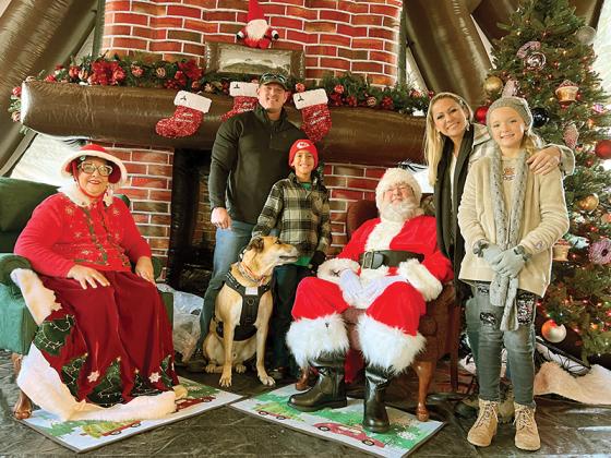 A family gets their photo taken with their pet in the Santa House at last year’s Light Up Ellijay. The annual yuletide festival on the square is this Friday on the day after Thanksgiving from 2–7:30 p.m., and is sponsored by Friends of Gilmer Animal Shelter. (FOGAS photo)