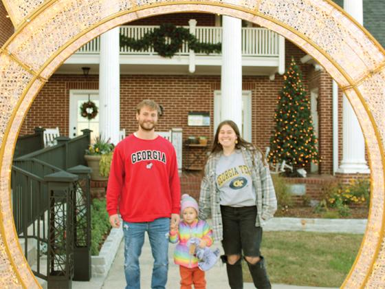 Tatum and Austin Chastain and their daughter, Juno, of Ellijay, walk through the illuminated Christmas bulb in front of the Gilmer Chamber Welcome Center during Light Up Ellijay. Mom and Dad appear to have divided loyalties before the kickoff of the state’s hottest football rivalry, Georgia Tech vs. Georgia, played Friday night.